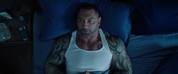 Movie still from “My Spy” (2020), directed by Peter Segal – A man laying in a bed with a tattoo on his chest; Medium shot, Overhead angle