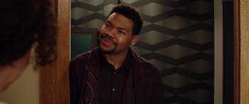 Movie still from “My Spy” (2020), directed by Peter Segal – A man in a brown shirt and a purple scarf; Close Up shot, Over the shoulder angle