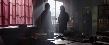 Movie still from “My Spy” (2020), directed by Peter Segal – Two men standing in front of a window in a dimly - lit room; Wide shot, Low angle