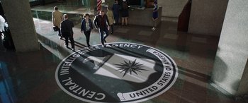 Movie still from “My Spy” (2020), directed by Peter Segal – A group of people walk around a cia sign; Wide shot, High angle