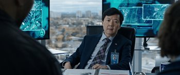 Movie still from “My Spy” (2020), directed by Peter Segal – A man sitting at a desk in front of a window; Medium shot, Over the shoulder angle