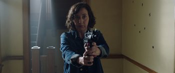 Movie still from “My Spy” (2020), directed by Peter Segal – A woman is holding a gun in a room; Medium shot, Over the shoulder angle