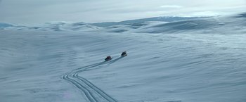 Movie still from “National Treasure” (2004), directed by Jon Turteltaub – A couple of trucks driving down a snow covered slope; Extreme Wide shot, High angle
