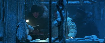 Movie still from “National Treasure” (2004), directed by Jon Turteltaub – A couple of people sitting on top of snow covered ground; Medium shot, Low angle