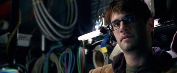 Movie still from “National Treasure” (2004), directed by Jon Turteltaub – A young man wearing a pair of glasses and headphones; Close Up shot, Over the shoulder angle