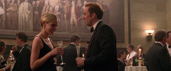 Movie still from “National Treasure” (2004), directed by Jon Turteltaub – A man and a woman are holding champagne glasses; Medium shot, Over the shoulder angle