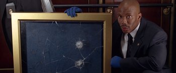 Movie still from “National Treasure” (2004), directed by Jon Turteltaub – A man holding a frame with a bullet hole in it; Close Up shot, Low angle