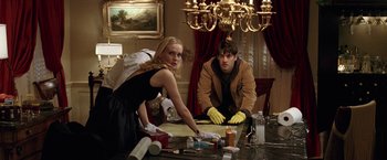 Movie still from “National Treasure” (2004), directed by Jon Turteltaub – A man and a woman cleaning a table in front of a chandelier; Medium shot, Low angle