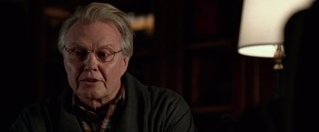 Movie still from “National Treasure” (2004), directed by Jon Turteltaub – An older man wearing glasses sitting in front of a book shelf; Close Up shot, Over the shoulder angle
