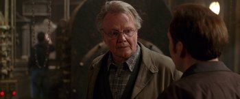 Movie still from “National Treasure” (2004), directed by Jon Turteltaub – An older man wearing glasses and a brown jacket; Close Up shot, Over the shoulder angle