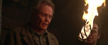 Movie still from “National Treasure” (2004), directed by Jon Turteltaub – An older man wearing glasses and a brown jacket; Close Up shot, Over the shoulder angle