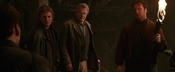 Movie still from “National Treasure” (2004), directed by Jon Turteltaub – A group of people standing next to each other in a dark room; Medium shot, Low angle