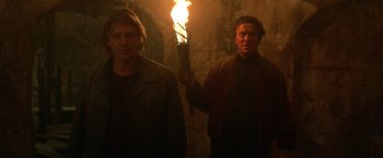 Movie still from “National Treasure” (2004), directed by Jon Turteltaub – Two men are holding a torch in the dark; Medium shot, Low angle