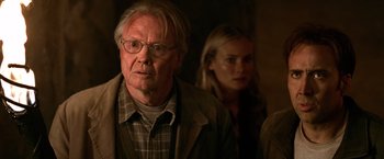 Movie still from “National Treasure” (2004), directed by Jon Turteltaub – An older man and a younger woman in a dimly - lit room; Close Up shot, Over the shoulder angle