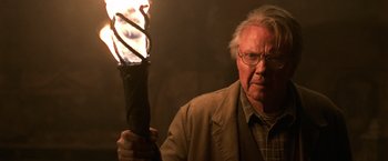 Movie still from “National Treasure” (2004), directed by Jon Turteltaub – An older man holding a lit candle in front of a dark background; Close Up shot, Low angle