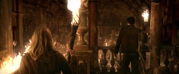 Movie still from “National Treasure” (2004), directed by Jon Turteltaub – A fireplace in the middle of a room with a person standing next to it; Wide shot, High angle