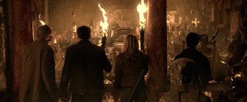 Movie still from “National Treasure” (2004), directed by Jon Turteltaub – A man and a woman standing in front of a fire; Wide shot, High angle