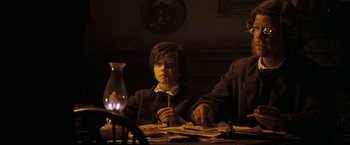 Movie still from “National Treasure: Book of Secrets” (2007), directed by Jon Turteltaub – A young man sitting at a table with a lit candle; Medium shot, Low angle