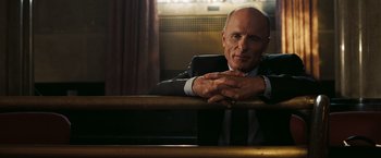 Movie still from “National Treasure: Book of Secrets” (2007), directed by Jon Turteltaub – An older man in a suit and tie leaning on a railing; Close Up shot, Low angle