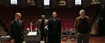 Movie still from “National Treasure: Book of Secrets” (2007), directed by Jon Turteltaub – Two men standing next to each other in front of an auditorium; Wide shot, Low angle