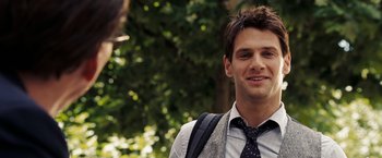 Movie still from “National Treasure: Book of Secrets” (2007), directed by Jon Turteltaub – A young man wearing a suit and tie smiling; Close Up shot, Over the shoulder angle