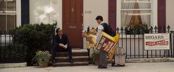 Movie still from “National Treasure: Book of Secrets” (2007), directed by Jon Turteltaub – A man is holding a poster while another man sits on the steps; Wide shot, High angle
