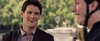 Movie still from “National Treasure: Book of Secrets” (2007), directed by Jon Turteltaub – A man in a business suit smiling for the camera; Close Up shot, Over the shoulder angle