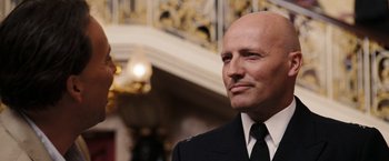 Movie still from “National Treasure: Book of Secrets” (2007), directed by Jon Turteltaub – A man in a suit and tie standing in front of a wall; Close Up shot, Low angle