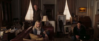Movie still from “National Treasure: Book of Secrets” (2007), directed by Jon Turteltaub – An older man standing next to a young woman on a couch; Wide shot, Over the shoulder angle
