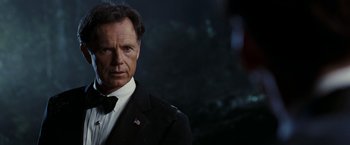 Movie still from “National Treasure: Book of Secrets” (2007), directed by Jon Turteltaub – A person wearing a suit and tie; Close Up shot, Over the shoulder angle