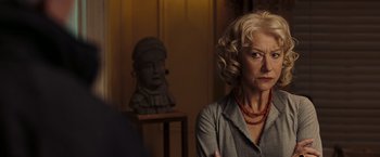 Movie still from “National Treasure: Book of Secrets” (2007), directed by Jon Turteltaub – An older woman in a gray shirt and red necklace; Close Up shot, Over the shoulder angle
