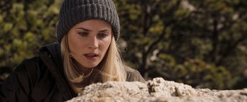 Movie still from “National Treasure: Book of Secrets” (2007), directed by Jon Turteltaub – A woman wearing a hat looking down at a rock; Close Up shot, Over the shoulder angle