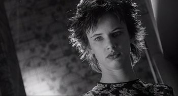 Movie still from “Natural Born Killers” (1994), directed by Oliver Stone – A young woman with short hair is posing for a picture; Close Up shot, Low angle