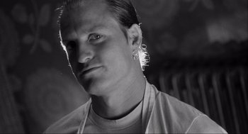 Movie still from “Natural Born Killers” (1994), directed by Oliver Stone – Black and white photograph of a man with a piercing; Close Up shot, Low angle