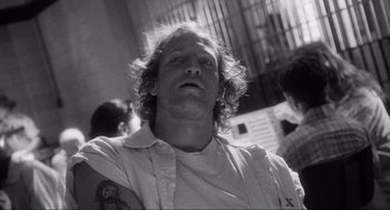 Movie still from “Natural Born Killers” (1994), directed by Oliver Stone – Black and white photograph of a man with tattoos; Close Up shot, Low angle