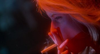 Movie still from “Natural Born Killers” (1994), directed by Oliver Stone – A woman is smoking a cigarette in the dark; Extreme Close Up shot, Low angle