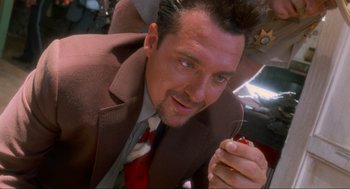 Movie still from “Natural Born Killers” (1994), directed by Oliver Stone – A person wearing a suit and tie; Close Up shot, Low angle