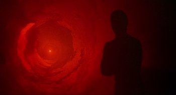 Movie still from “Natural Born Killers” (1994), directed by Oliver Stone – A man standing in front of a wall with a hole in it; Extreme Wide shot, High angle