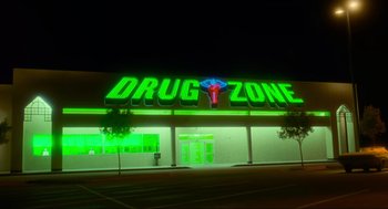 Movie still from “Natural Born Killers” (1994), directed by Oliver Stone – A neon sign that reads " drug zone " on the side of a building; Extreme Wide shot, Low angle