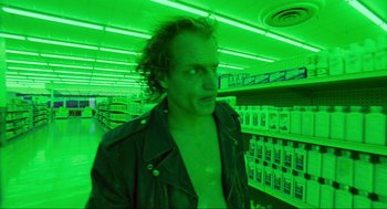 Movie still from “Natural Born Killers” (1994), directed by Oliver Stone – A man in a green light in a grocery store; Medium shot, Low angle