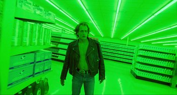 Movie still from “Natural Born Killers” (1994), directed by Oliver Stone – A man standing in a grocery store with green lighting; Wide shot, Low angle