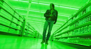 Movie still from “Natural Born Killers” (1994), directed by Oliver Stone – A man standing in the middle of an aisle in a store; Wide shot, Low angle