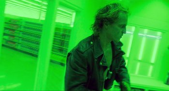 Movie still from “Natural Born Killers” (1994), directed by Oliver Stone – A man in a black leather jacket standing next to a green wall; Medium shot, Low angle