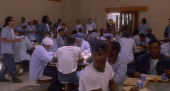 Movie still from “Natural Born Killers” (1994), directed by Oliver Stone – A group of men sitting at a table eating food; Wide shot, High angle