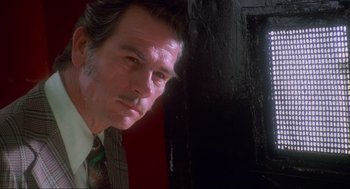 Movie still from “Natural Born Killers” (1994), directed by Oliver Stone – A person wearing a suit and tie; Close Up shot, Low angle