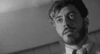 Movie still from “Natural Born Killers” (1994), directed by Oliver Stone – Black and white photograph of a man in a suit and tie; Close Up shot, Low angle