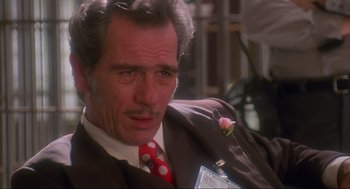 Movie still from “Natural Born Killers” (1994), directed by Oliver Stone – A person wearing a suit and tie; Close Up shot, Over the shoulder angle