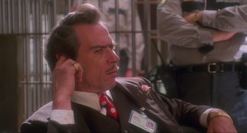 Movie still from “Natural Born Killers” (1994), directed by Oliver Stone – A man in a suit and tie holding a cell phone to his ear; Close Up shot, Over the shoulder angle