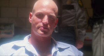 Movie still from “Natural Born Killers” (1994), directed by Oliver Stone – A man with a shaved head is looking at the camera; Close Up shot, Low angle