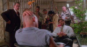 Movie still from “Natural Born Killers” (1994), directed by Oliver Stone – A group of people in a jail cell; Wide shot, Over the shoulder angle